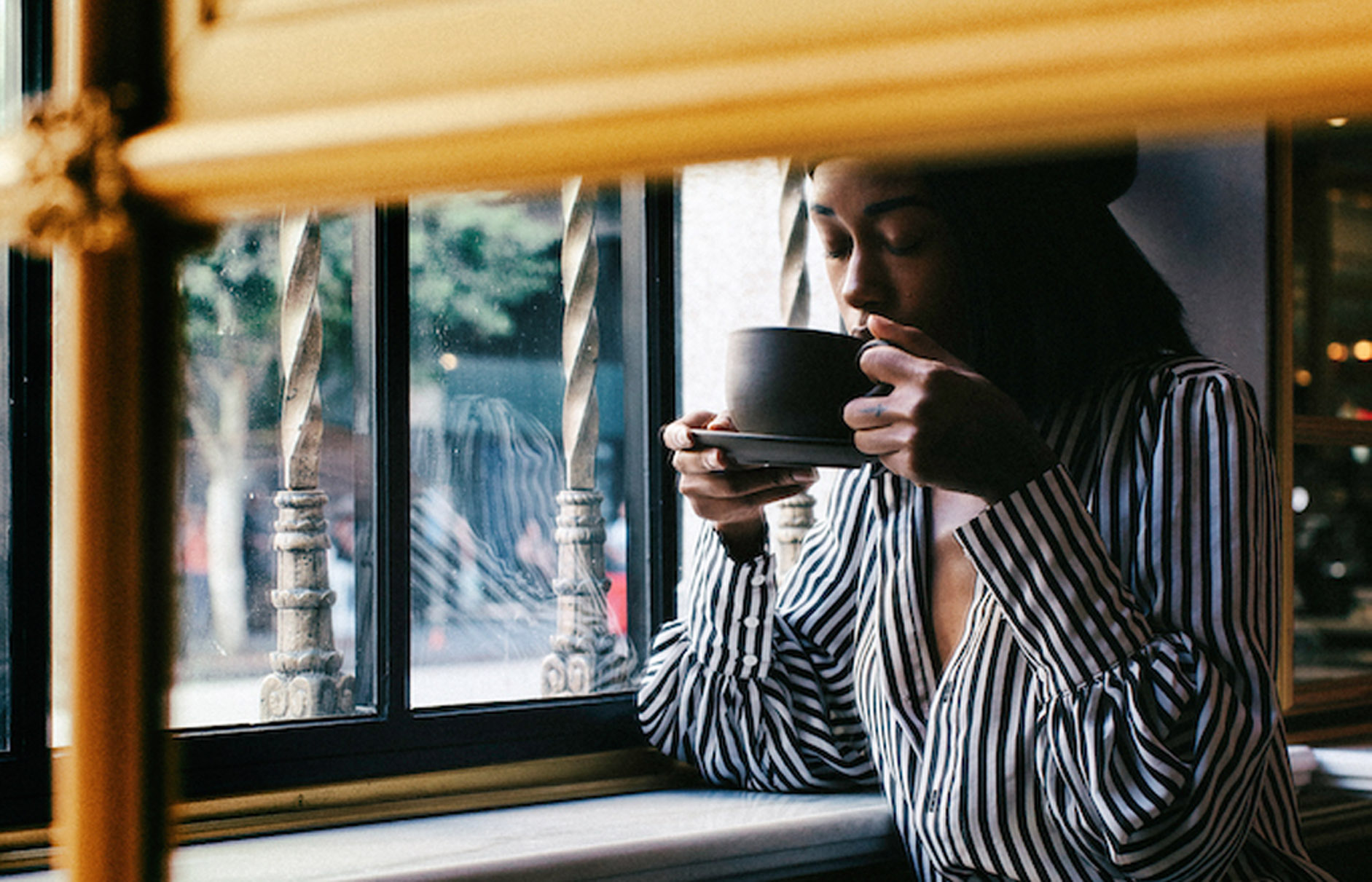 Woman drinking a coffee by a window