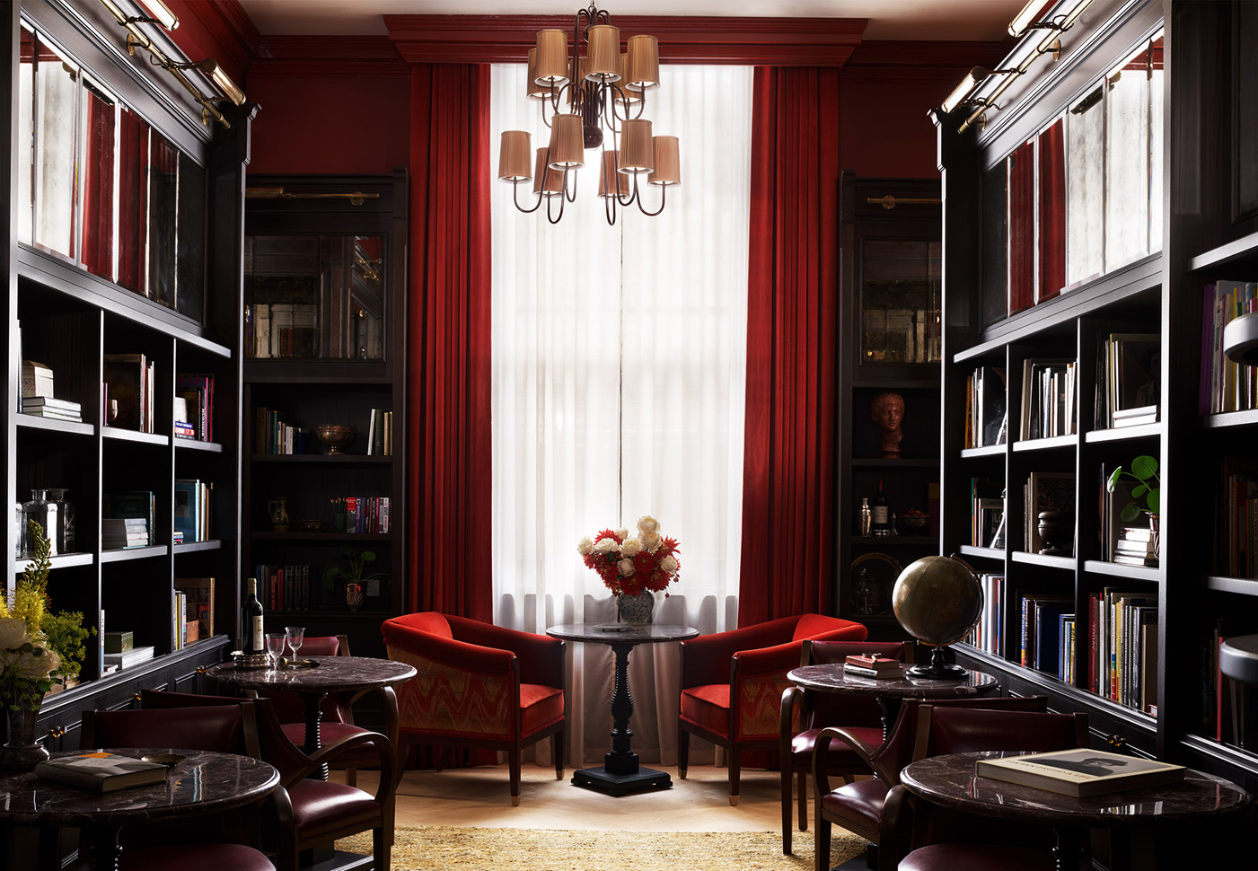 Elegant library dining room with a focus point on seating with large red chairs and floral center piece